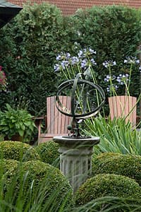 Tuinbeeld met zitplek, buxusvormen en ornament